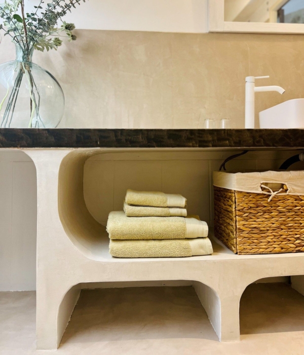 Yellow linen napkins are arranged in a concrete display case with a wicker basket.