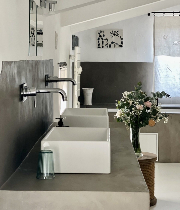 An elegant white sink with a dried flower in a wicker vase.