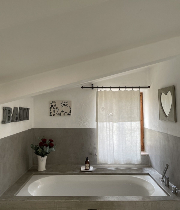 Stone bathtub in a rustic bathroom with curtain and decorations.