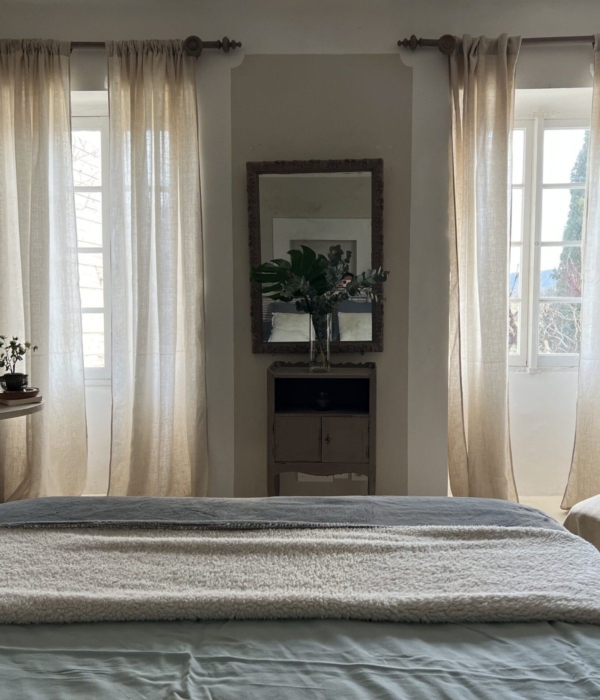 Cozy room with linen curtains, a mirror and comfortable bedding.