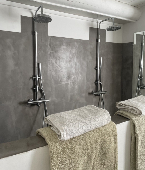 Modern shower with white towels and a textured grey and white wall.