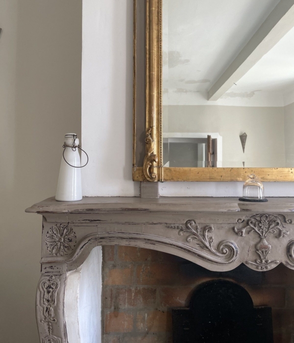 An elegant gilded mirror and a carved fireplace adorn this charming antique living room.
