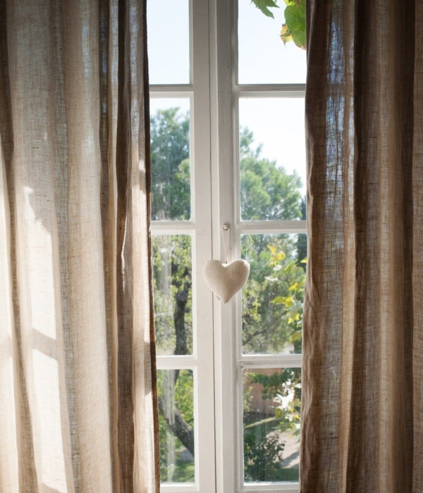 Beige linen curtain in front of a window with a felt heart attached.