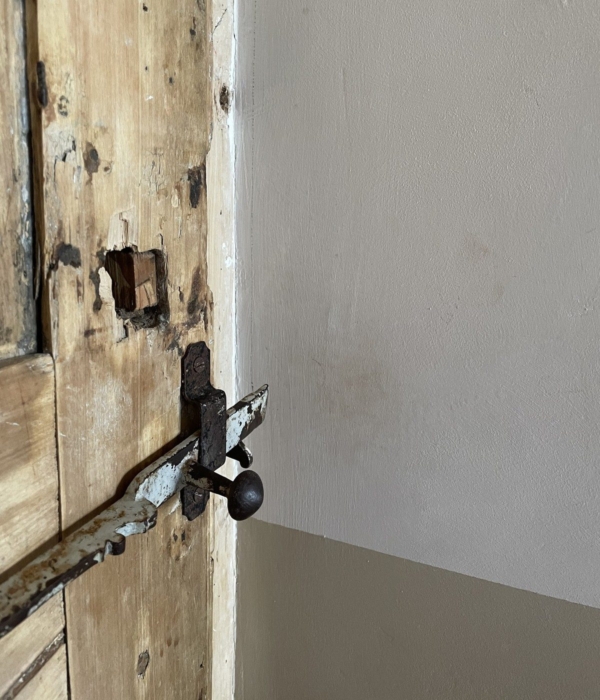 Eine alte Holztür mit einem rostigen Schloss und Anzeichen von Fäulnis.