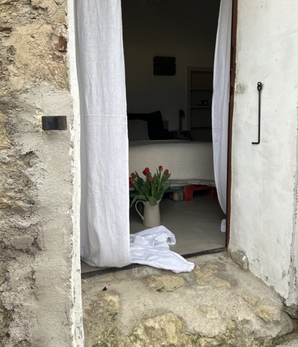 Eine Steintür öffnete sich zu einem hellen Raum mit einem Bett und roten Blumen.