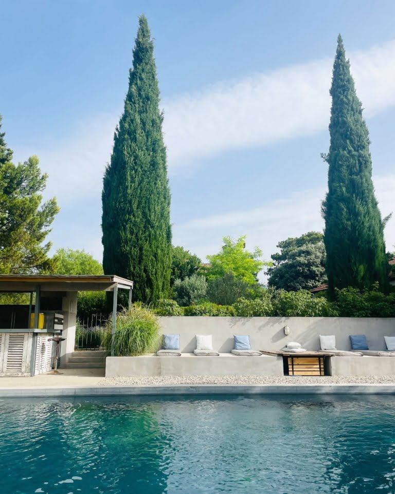 Une piscine paisible avec des cyprès majestueux et un espace détente confortable.