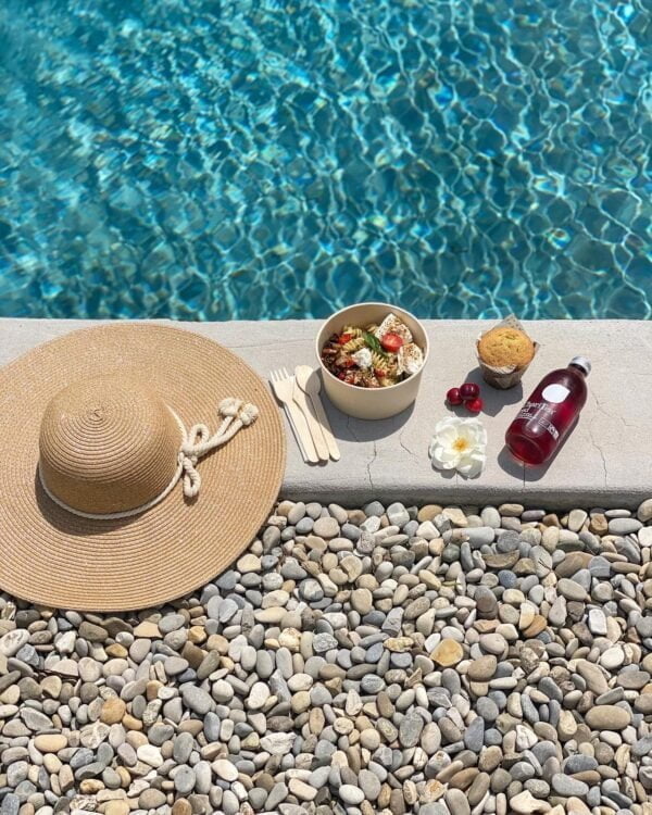 a table topped with a bucket of food next to a pool of water