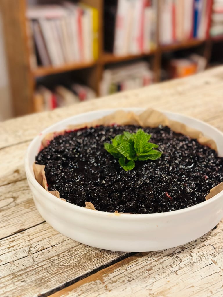 Ein köstlicher Blaubeerkuchen mit frischer Minze auf einem rustikalen Tisch.