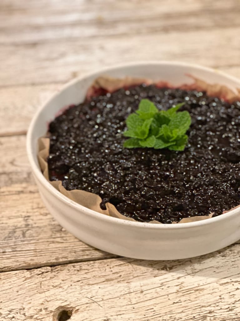 A beautiful blackberry jam on parchment paper, decorated with a fresh mint leaf.