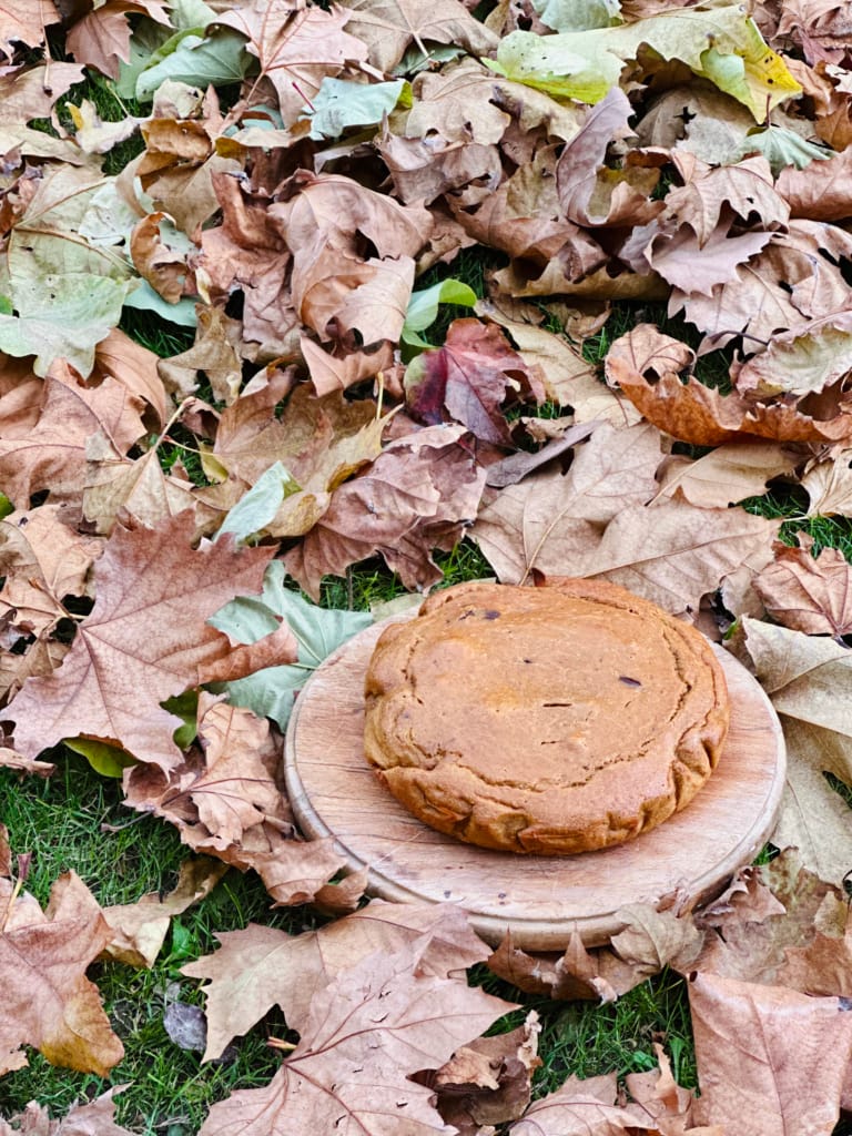 Un biscuit chaud posé sur une planche de bois parmi les feuilles d'automne.