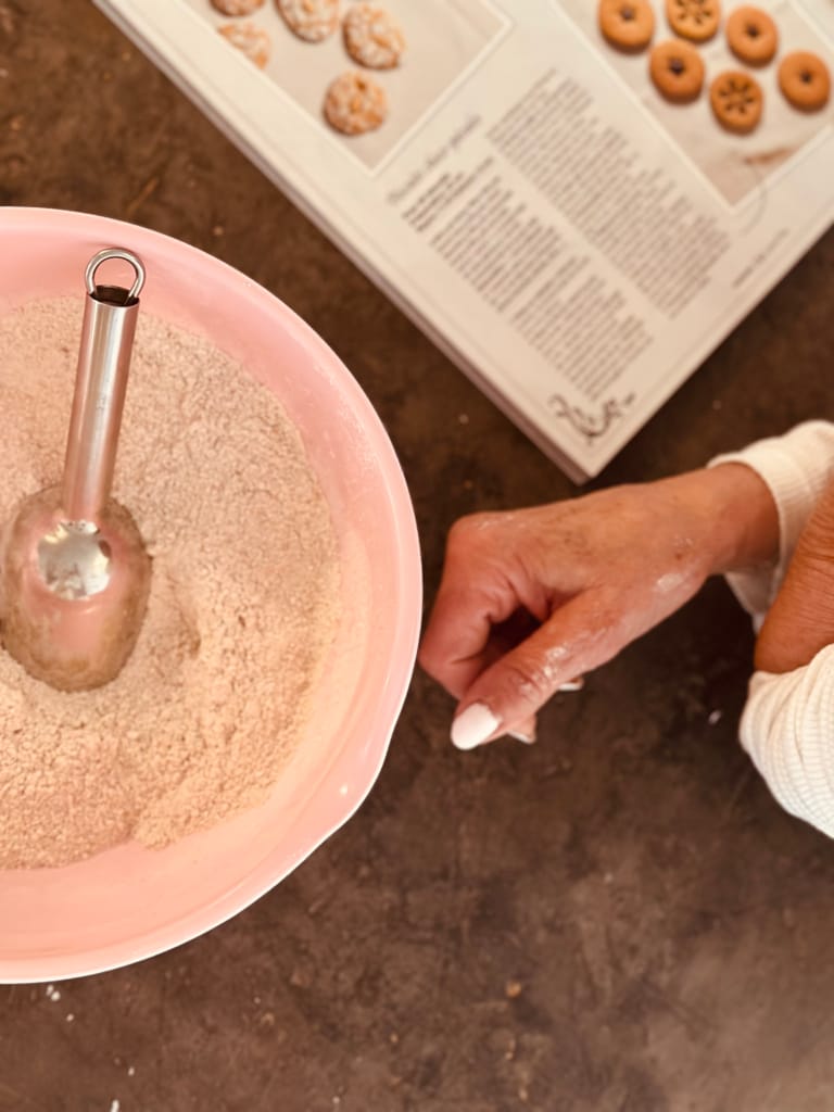 Une main prépare une recette de biscuits dans un bol avec une spatule.