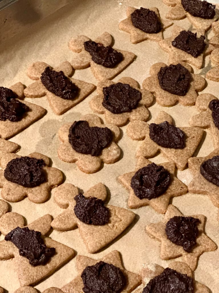 Des biscuits décorés de chocolat fondu, prêts à être dorés au four.