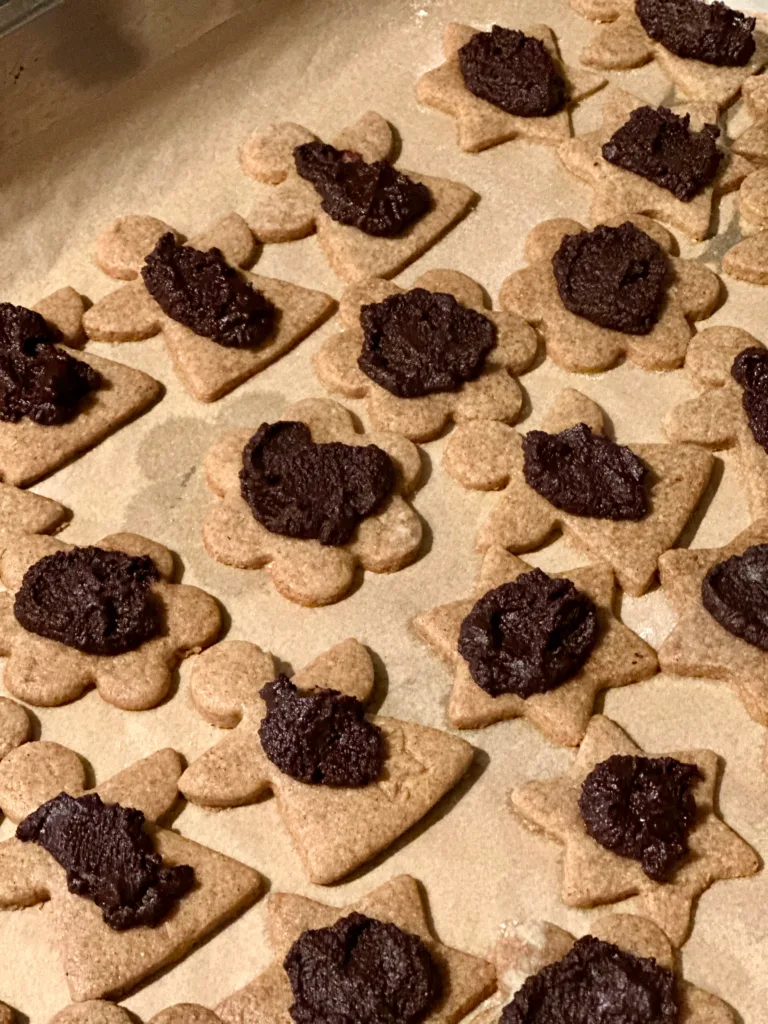 Cookies decorated with melted chocolate, ready to be browned in the oven.