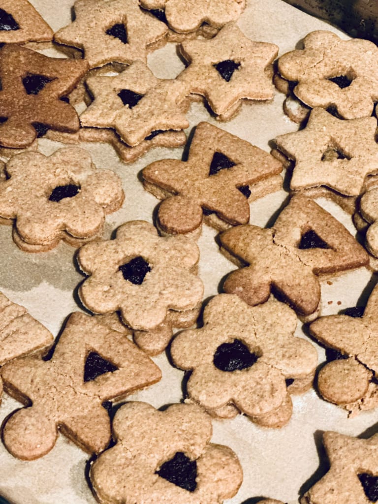 De nombreuses biscuits décorés en forme d'étoiles et de fleurs sont disposés sur une plaque.