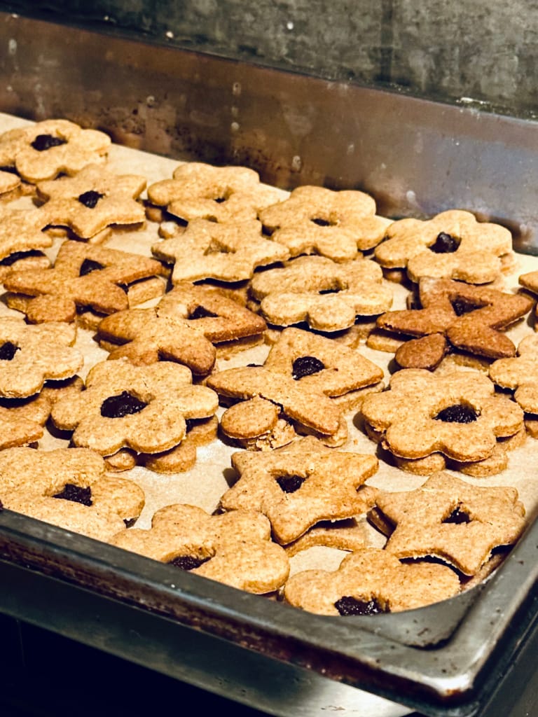Une grande quantité de biscuits en forme de fleurs, cuits et prêts à être dégustés.