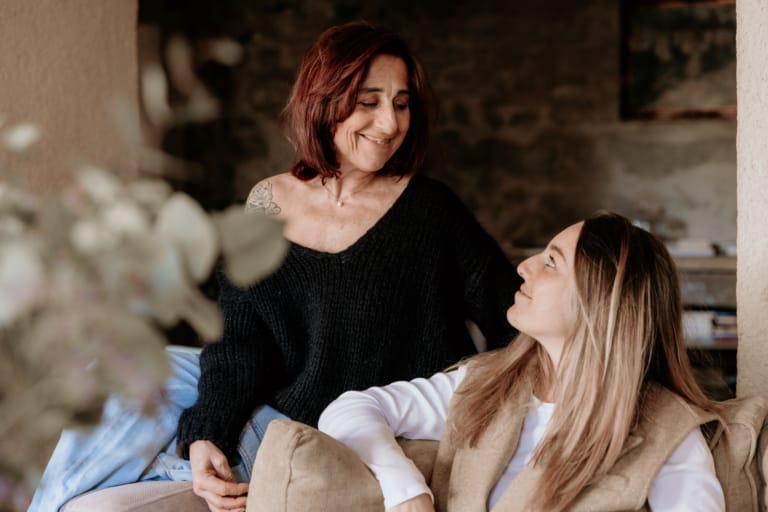 Une mère et sa fille partagent un moment de tendresse dans un intérieur chaleureux.