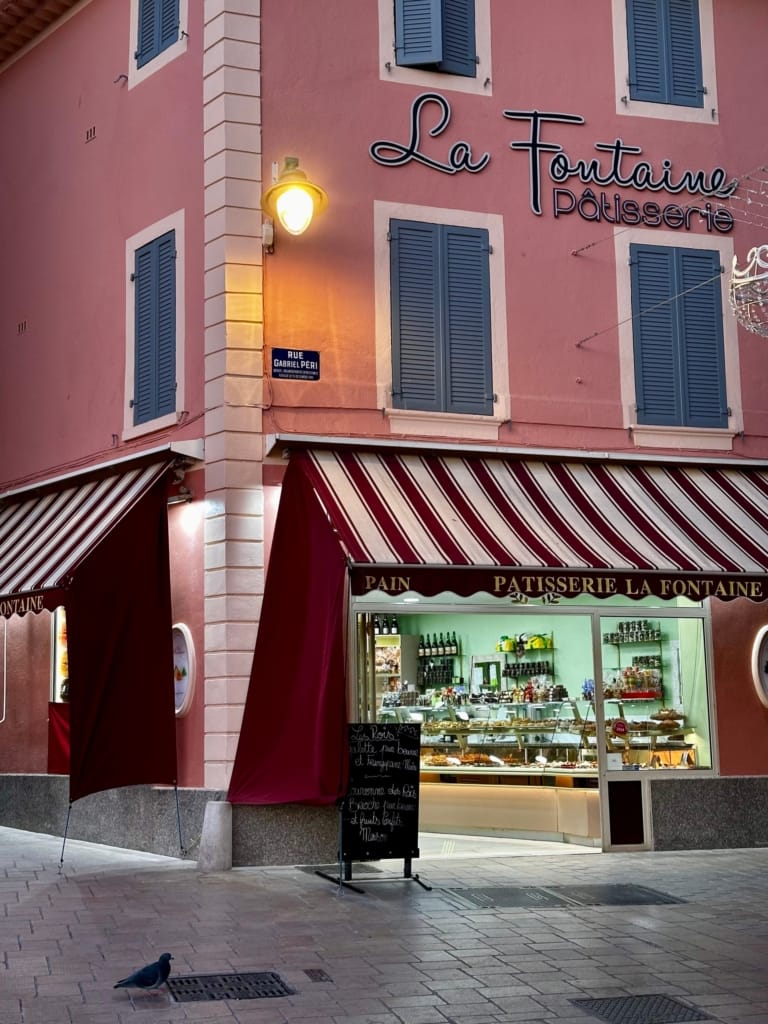 Pâtisserie La Fontaine, a charming pink shop with a red awning and appetizing pastries.