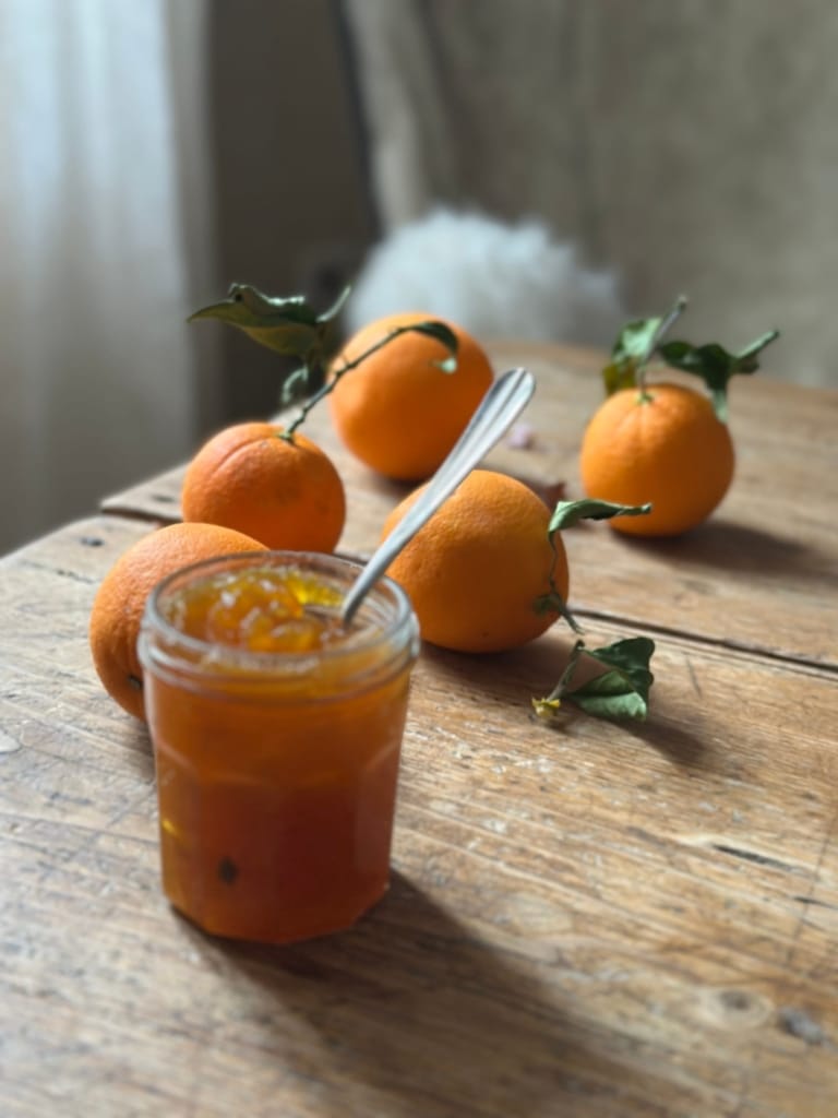 Delicious candied orange on a wooden table, with fresh oranges.