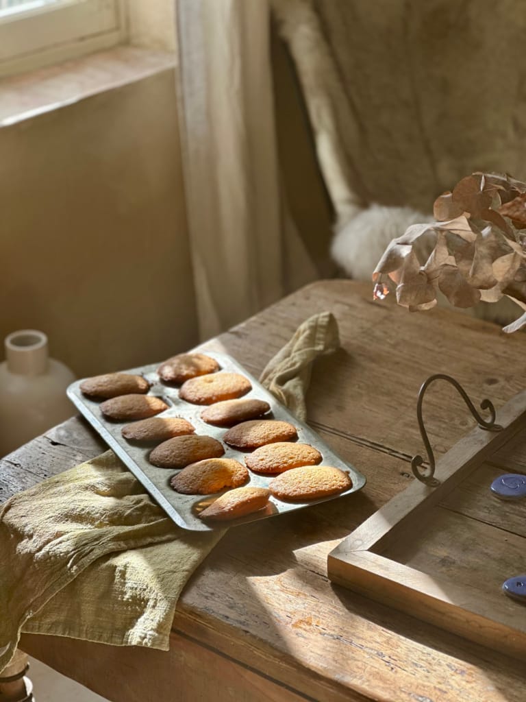 Goldene Madeleines auf einem Holztisch, eine warme und rustikale Atmosphäre.
