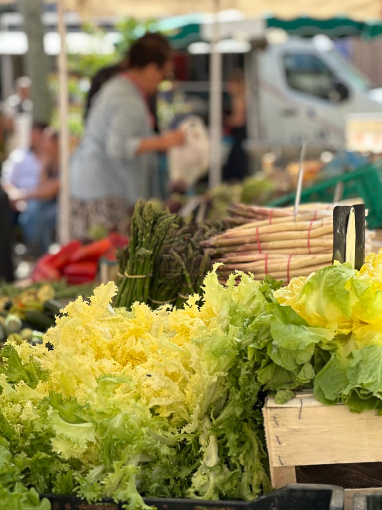 Frisches Gemüse, darunter Salat und Spargel, auf einem Markt.