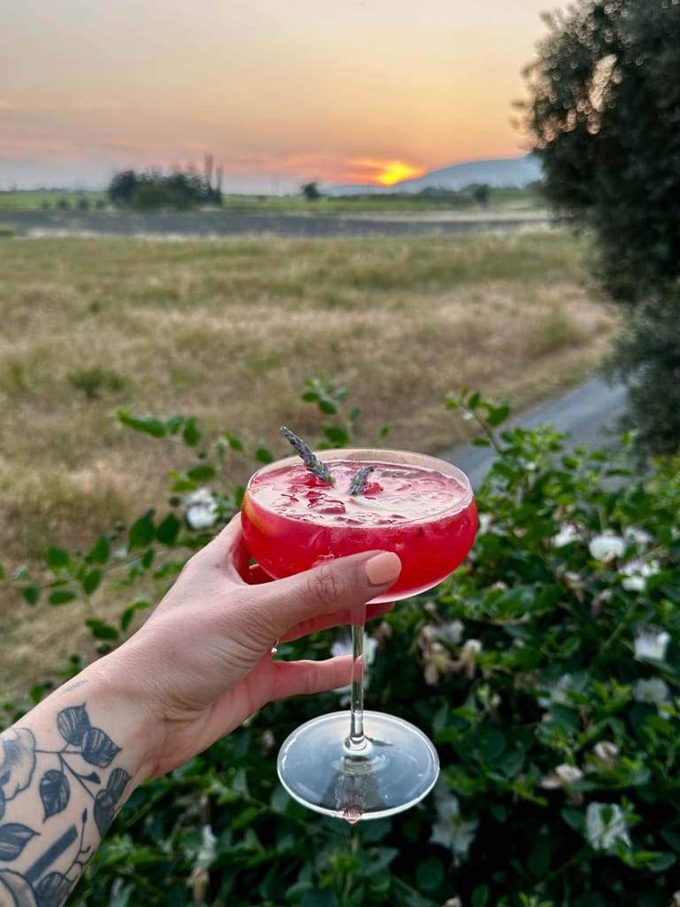 Ein Glas rosa Cocktail bei Sonnenuntergang, eine friedliche und entspannende Atmosphäre.