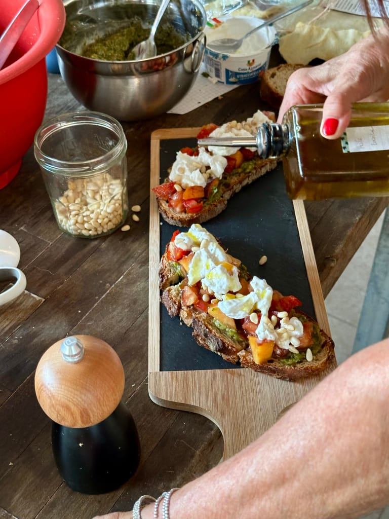 Bestreichen Sie eine Scheibe Brot mit Burrata, Tomaten und Mozzarella und geben Sie dann Olivenöl darüber.