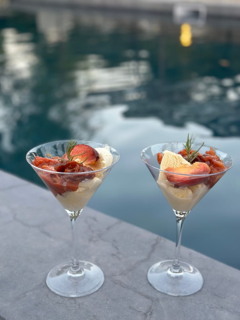 Zwei Verrines mit Pfirsichen und Rosen, ein sommerlicher Genuss am Poolrand.
