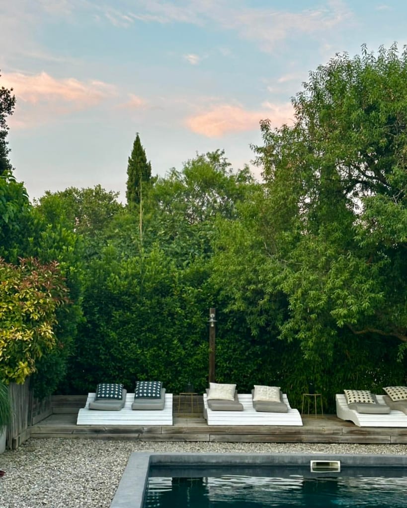 Ein friedlicher Swimmingpool mit Sonnenliegen unter einem pastellfarbenen Himmel bei Sonnenuntergang.