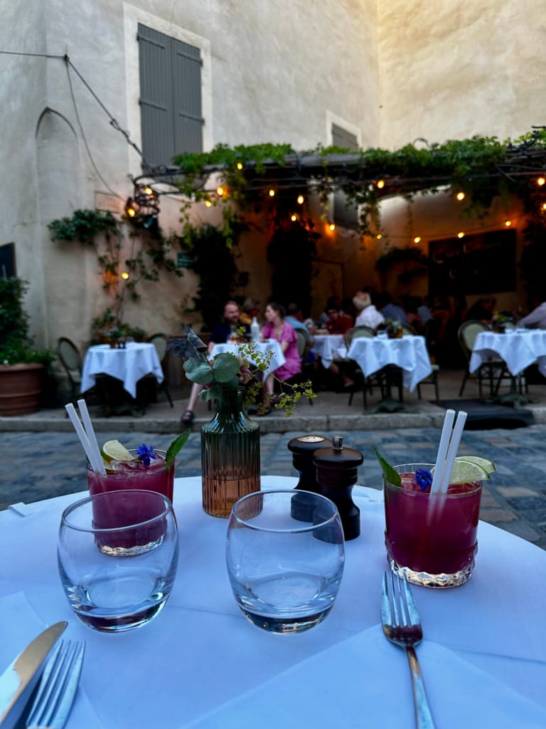 Une table dressée en terrasse illuminée, ambiance conviviale et cocktails colorés.