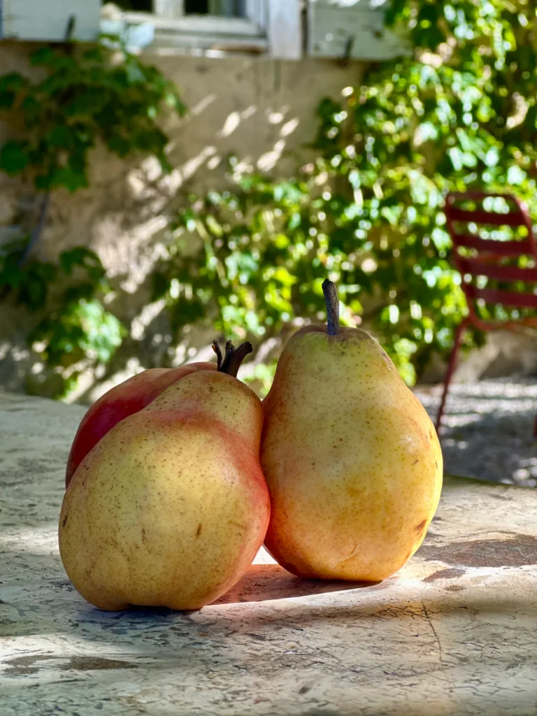Deux poires mûres et juteuses posées sur une table en plein jour.