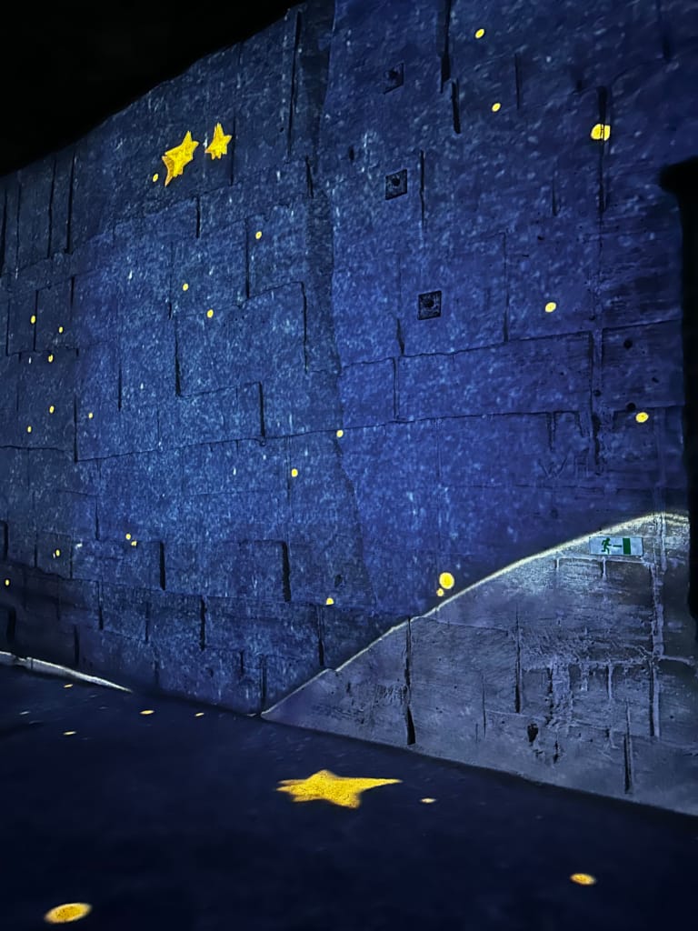 Mur bleu illuminé par des étoiles dorées, créant une ambiance nocturne et mystérieuse.