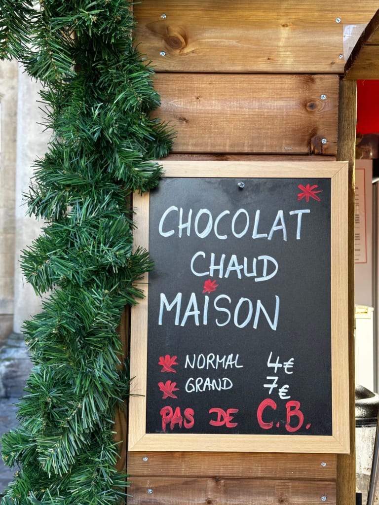 Panneau indiquant le chocolat chaud de la maison avec les prix.