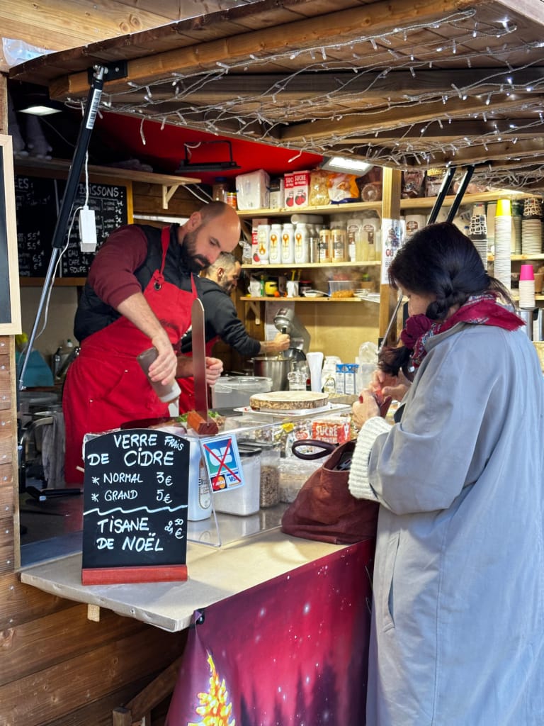 Un vendeur de cidre chaud et de tisane de Noël dans un marché de Noël illuminé.
