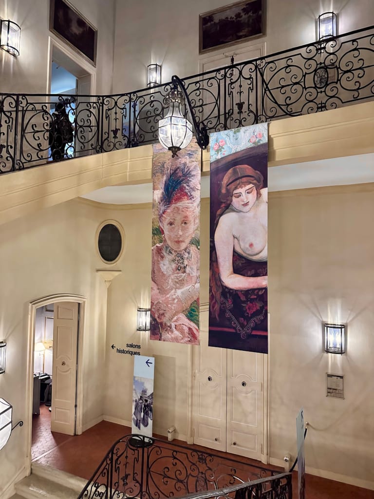 Vue intérieure d'un couloir d'hôtel avec des tableaux accrochés.
