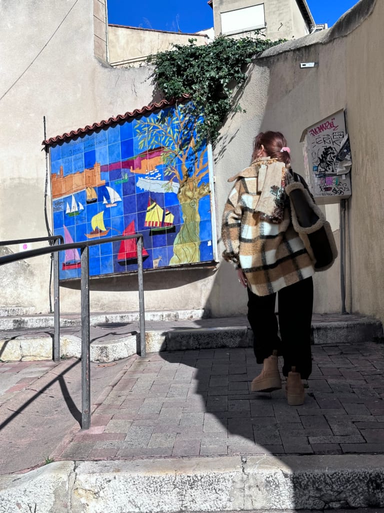 Une femme regarde une fresque marine colorée sur un mur de la ville.