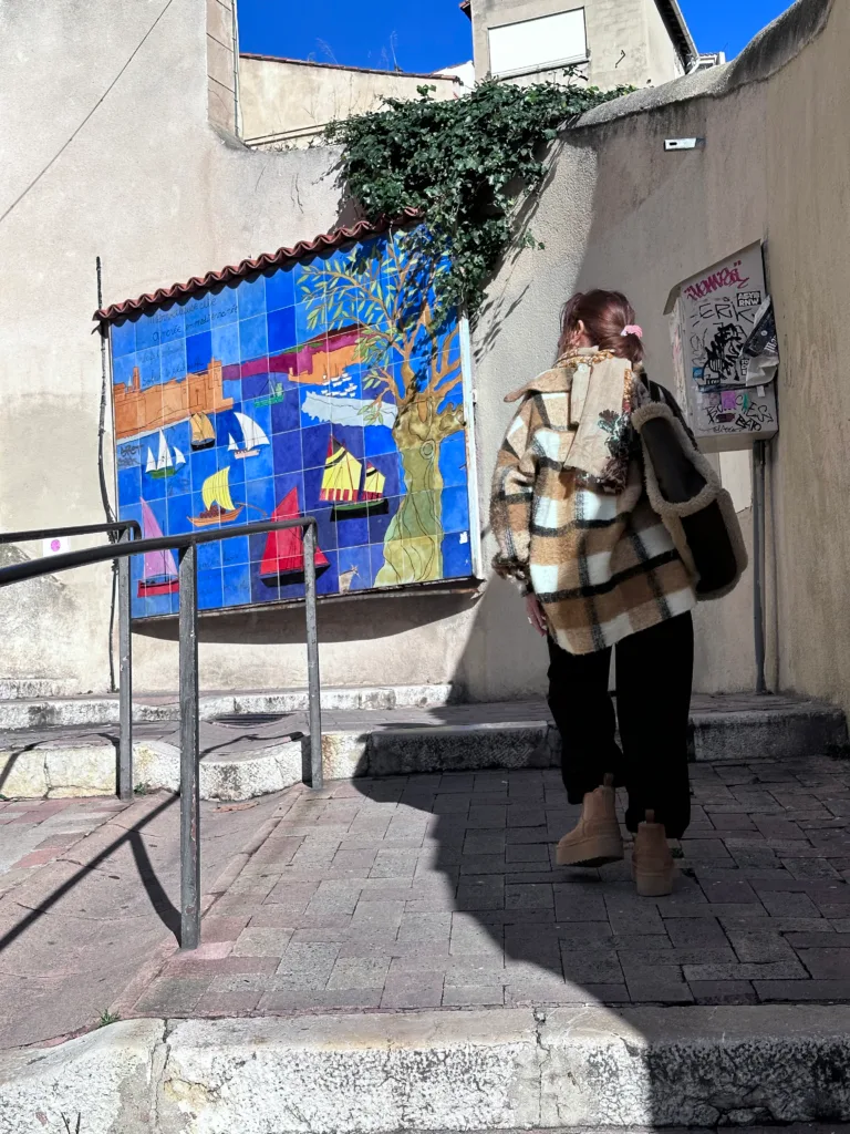 Une femme regarde une fresque marine colorée sur un mur de la ville.