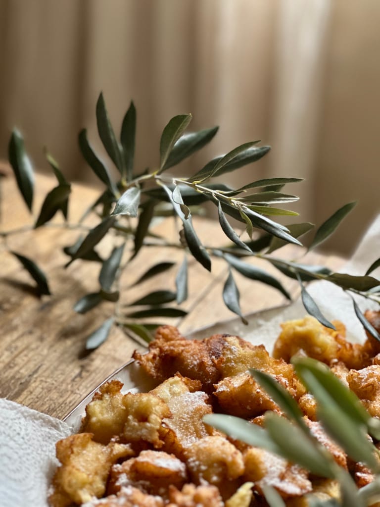 Des beignets moelleux et sucrés, décorés de feuilles d'olives, sur une table rustique.