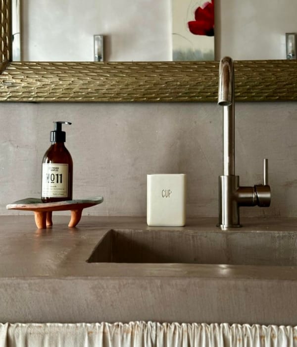 Lavabo moderne avec distributeur de savon, tasse et accessoires décoratifs.