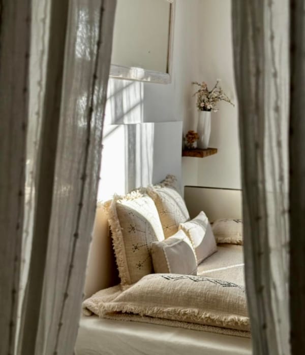 Un coin douillet et lumineux, décoré de coussins et rideaux, invite à la détente.