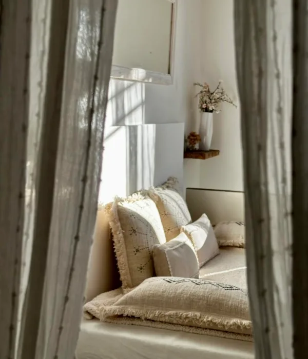 Un coin douillet et lumineux, décoré de coussins et rideaux, invite à la détente.