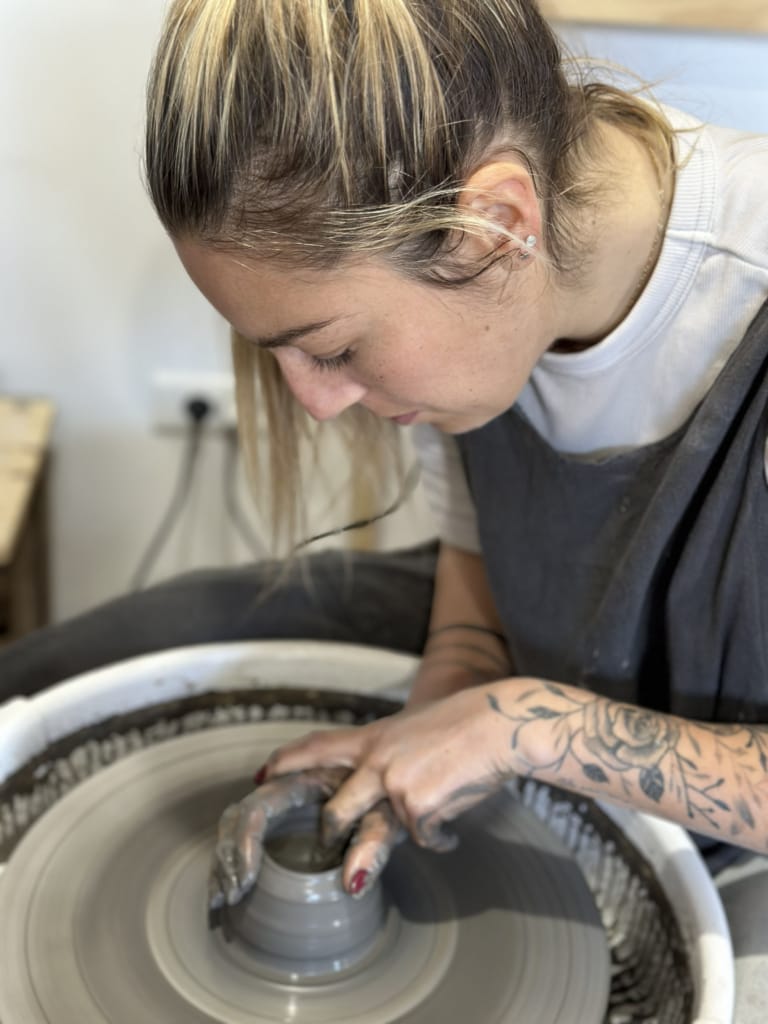 Une céramiste concentrée façonne une pièce sur un tour de potier.