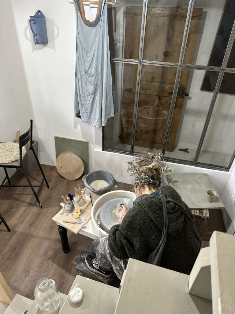 Une céramiste travaille sur son tour de poterie dans son atelier, concentrée sur sa création.