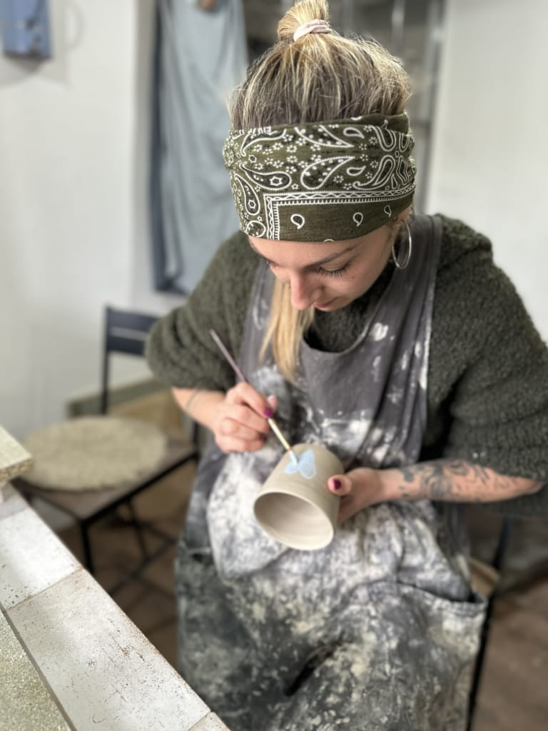 Une artiste travaille sur une poterie, concentrée et créative dans son atelier.