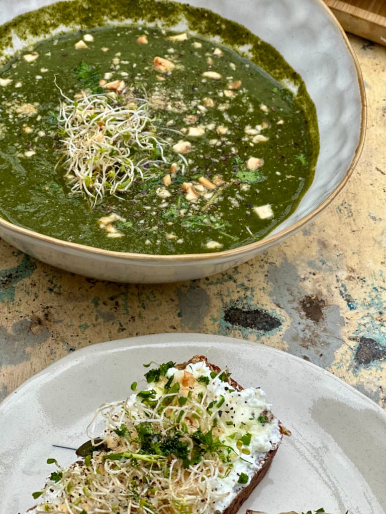 Une soupe verte crémeuse et un toast aux microgreens, un repas sain et délicieux.