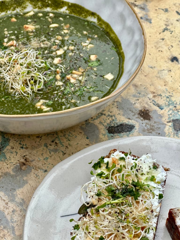 Une soupe verte et une tartine garnie de micro-greens, un repas sain et savoureux.