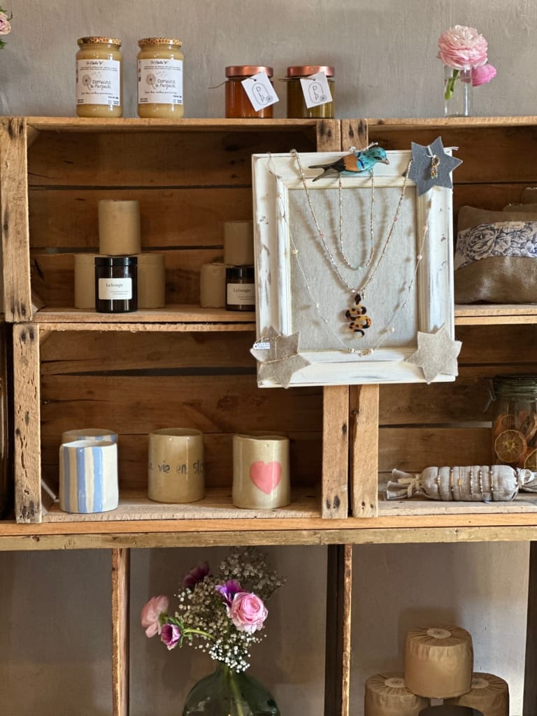 Étagère en bois avec des produits artisanaux, bougies et décorations.