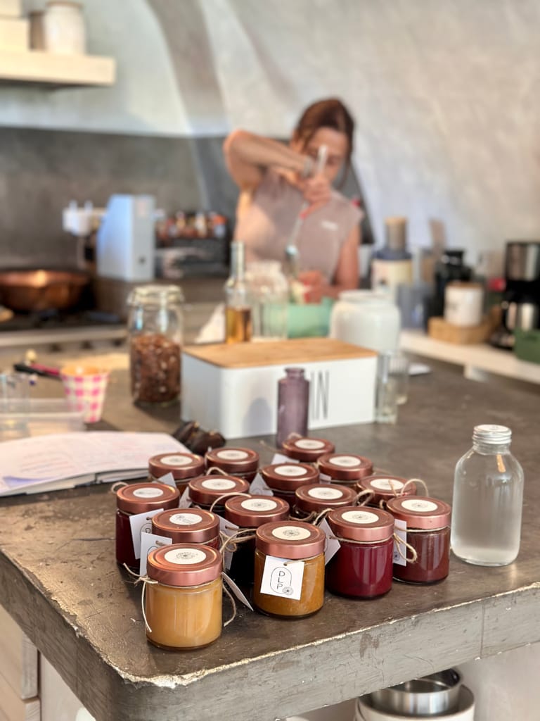 De nombreuses petites potiches de confitures artisanales sont disposées sur un comptoir de cuisine.