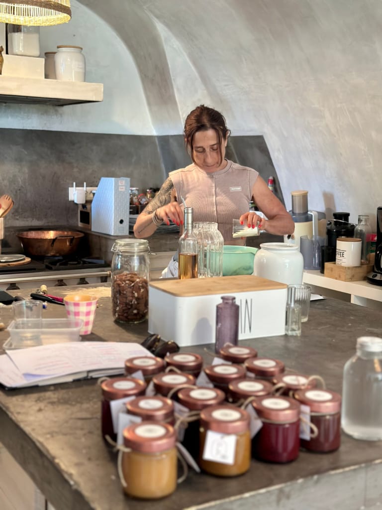 Une femme prépare des infusions dans un café artisanal avec des bocaux décoratifs.