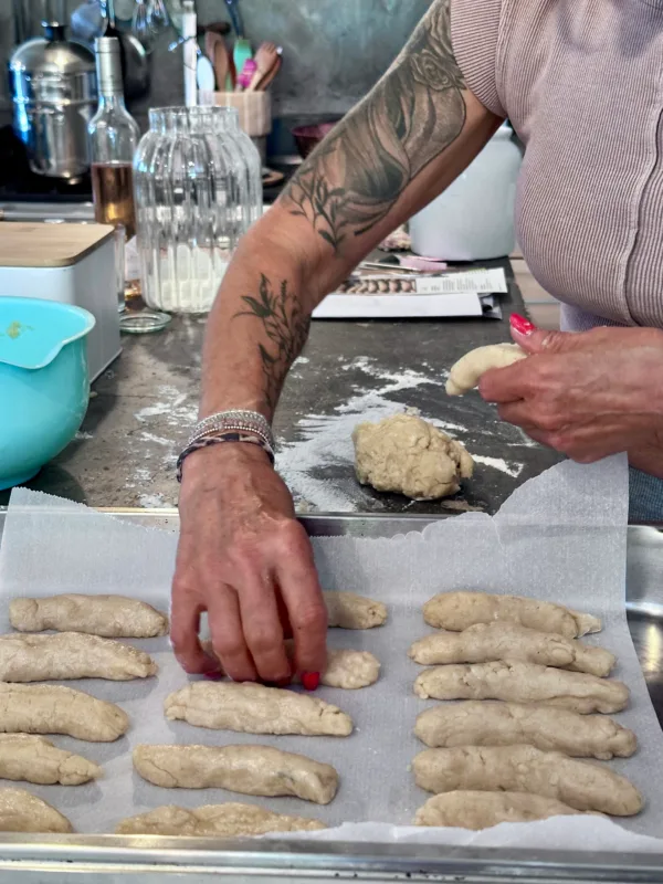 Une femme façonne de la pâte à pain sur une plaque recouverte de papier sulfurisé.