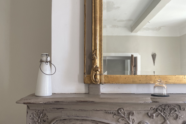 Un élégant miroir doré et un foyer sculpté ornent ce salon ancien et charmant.